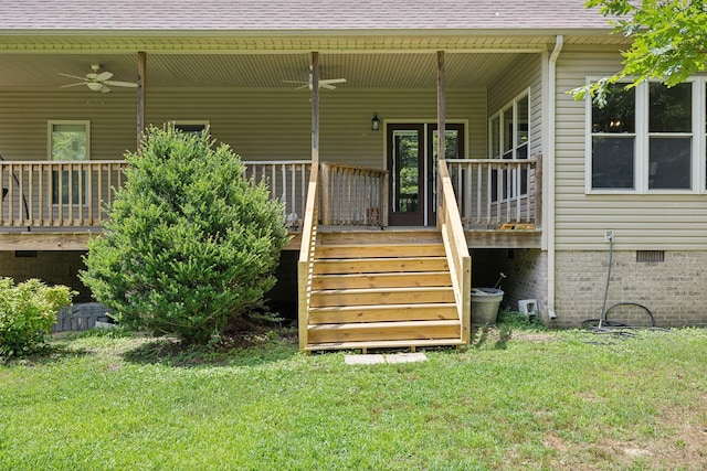 doorway to property with ceiling fan, a wooden deck, and a lawn