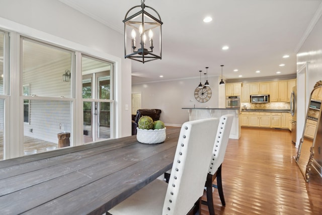 dining room with an inviting chandelier, crown molding, and light hardwood / wood-style flooring