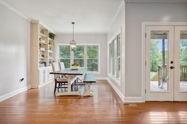 dining area with hardwood / wood-style flooring, a healthy amount of sunlight, crown molding, and french doors