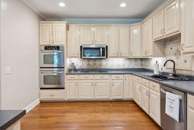 kitchen with light wood-type flooring, stainless steel appliances, backsplash, and sink