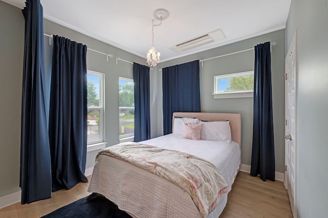 bedroom with multiple windows, light wood finished floors, and an inviting chandelier