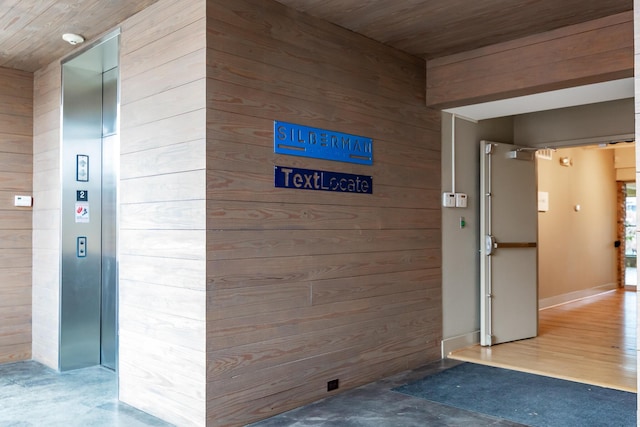 hallway featuring wooden ceiling, concrete floors, and wooden walls