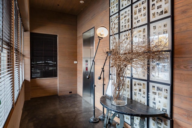 corridor featuring wooden ceiling, wood walls, and concrete flooring