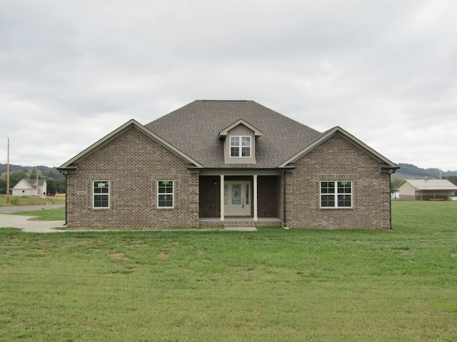 view of front of house featuring a front yard, brick siding, and roof with shingles