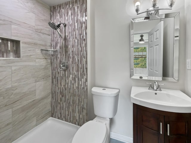 bathroom with tiled shower, vanity, and toilet