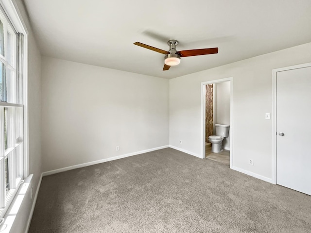 unfurnished bedroom with connected bathroom, ceiling fan, and dark carpet