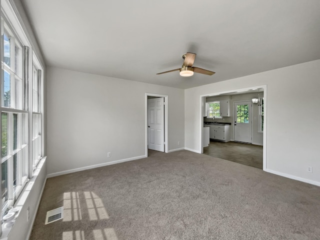 carpeted empty room with ceiling fan with notable chandelier