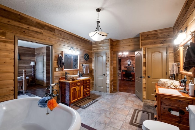 bathroom with a bath, vanity, and wooden walls