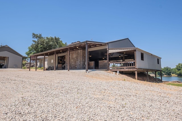 back of property with a water view and an outdoor structure