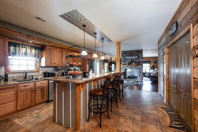 kitchen with light stone countertops, pendant lighting, a center island, and a kitchen breakfast bar