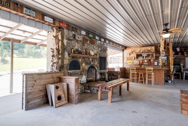 interior space with a stone fireplace, ceiling fan, and concrete floors