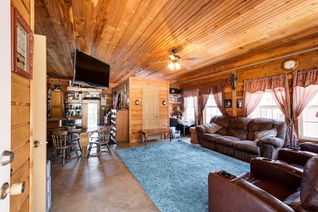 living room with ceiling fan, wood walls, wooden ceiling, and concrete flooring