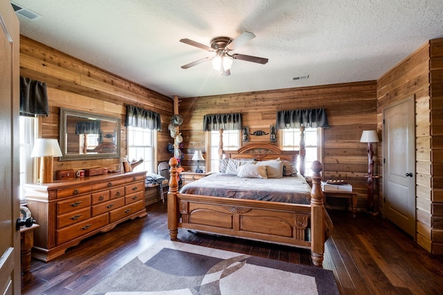 bedroom featuring multiple windows, a textured ceiling, dark hardwood / wood-style floors, and ceiling fan