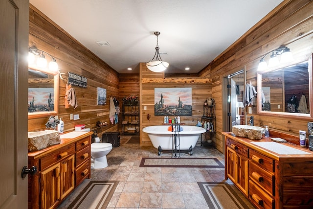 bathroom featuring vanity, toilet, a tub to relax in, and wooden walls