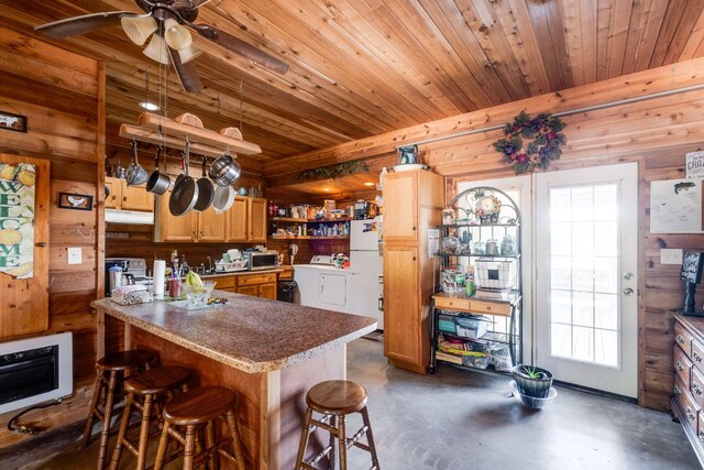 kitchen with a breakfast bar, white fridge, washer / dryer, kitchen peninsula, and heating unit