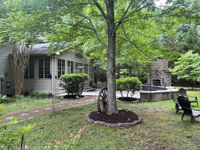 view of yard featuring a patio and an outdoor stone fireplace