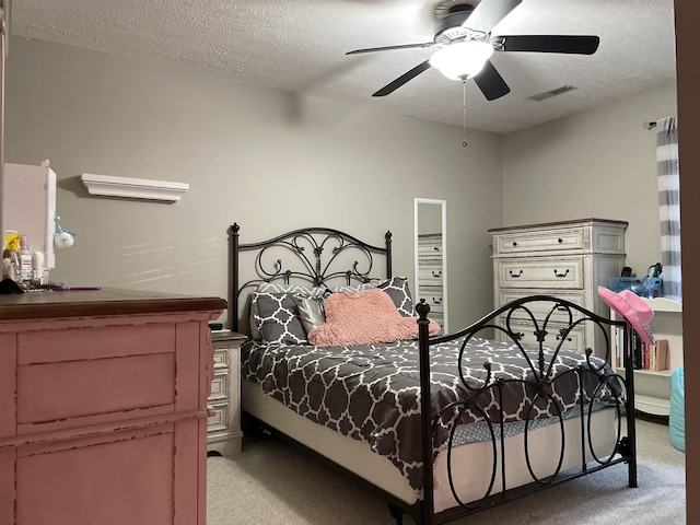 bedroom featuring light carpet, a textured ceiling, and ceiling fan