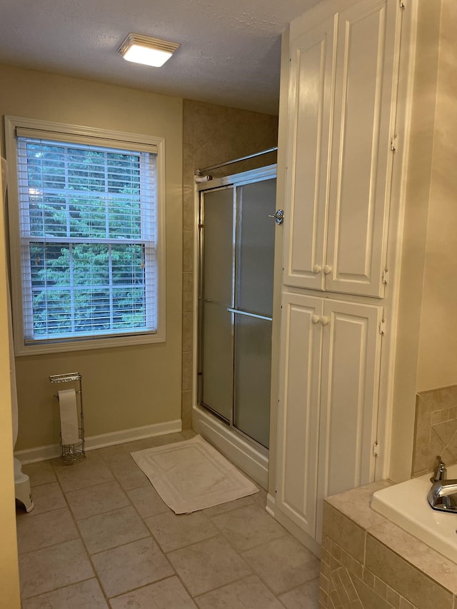 bathroom featuring tile patterned floors, a shower with door, and a textured ceiling