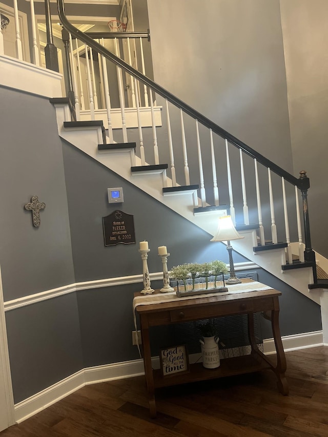 stairs featuring hardwood / wood-style flooring and a towering ceiling