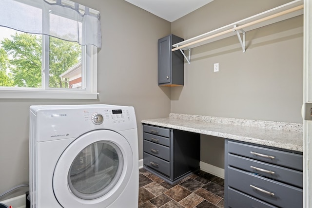 laundry room featuring washer / dryer, cabinets, and dark tile flooring