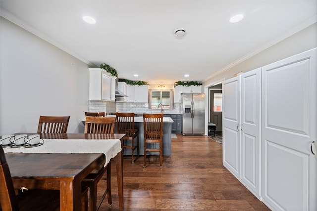 dining space featuring sink, ornamental molding, and dark hardwood / wood-style flooring