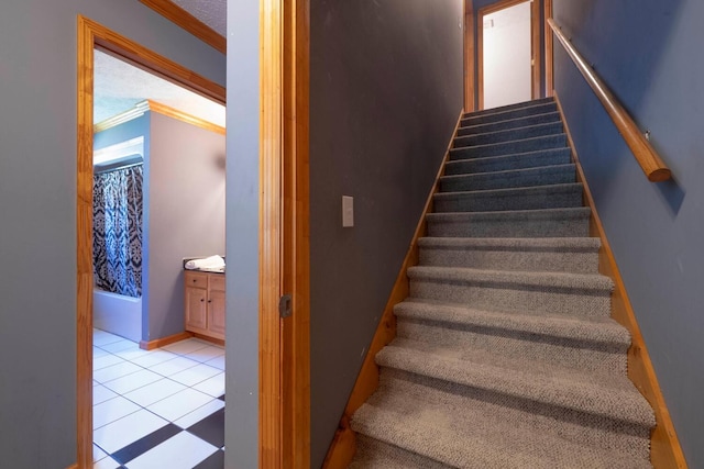 staircase featuring tile patterned flooring, a textured ceiling, and ornamental molding