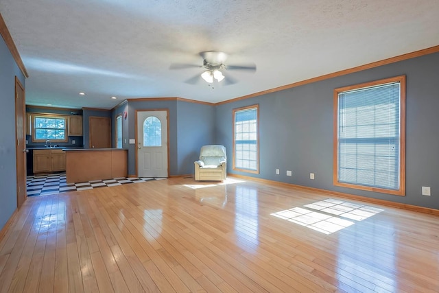 unfurnished living room featuring ceiling fan, light hardwood / wood-style floors, ornamental molding, and sink