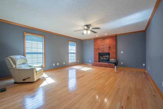 unfurnished living room with ceiling fan, light hardwood / wood-style floors, ornamental molding, and a fireplace