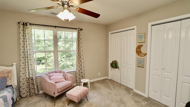 living area with light carpet and ceiling fan