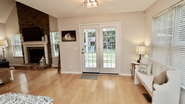 entryway with light hardwood / wood-style floors and a stone fireplace