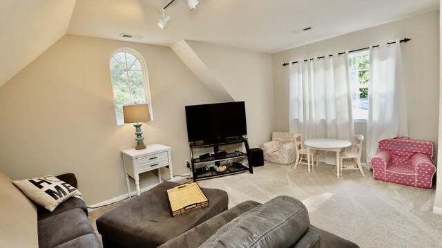 living room featuring rail lighting, light colored carpet, and lofted ceiling