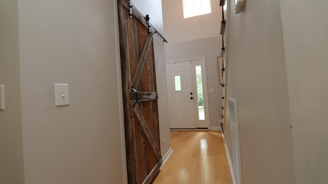 entryway with a barn door, a wealth of natural light, and light hardwood / wood-style flooring