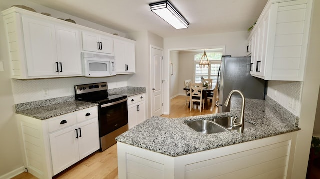 kitchen featuring white cabinets, light stone countertops, kitchen peninsula, and appliances with stainless steel finishes