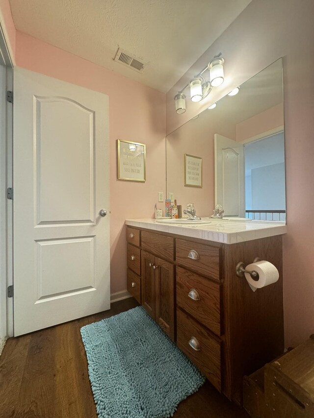 bathroom with vanity, wood-type flooring, and a textured ceiling