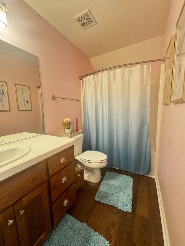 bathroom featuring vanity, wood-type flooring, vaulted ceiling, and toilet