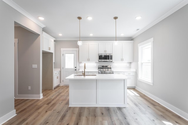 kitchen featuring pendant lighting, white cabinetry, stainless steel appliances, sink, and a center island with sink