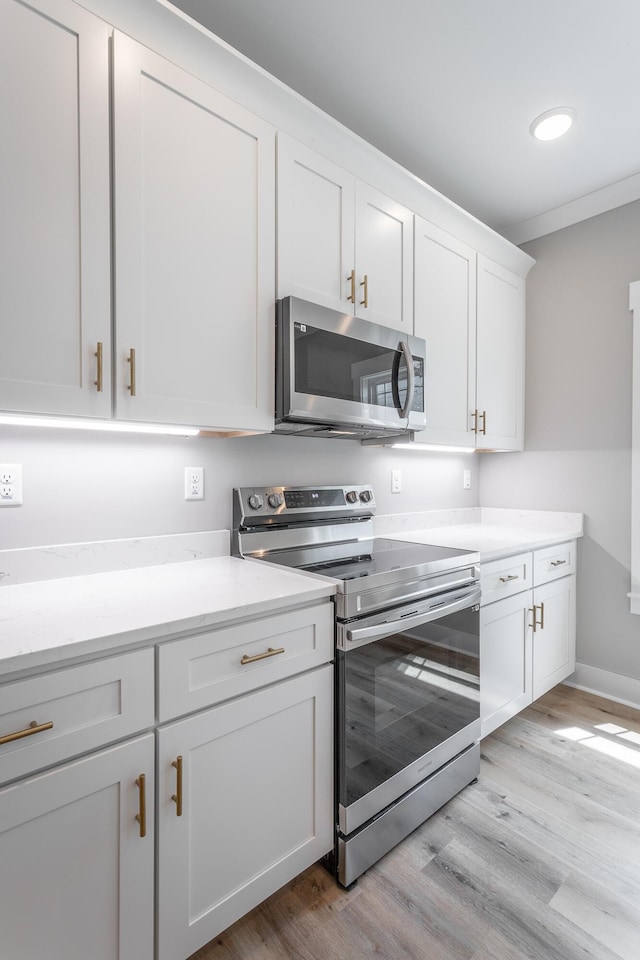 kitchen featuring crown molding, light wood-type flooring, white cabinetry, and stainless steel appliances