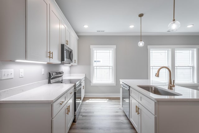 kitchen with a kitchen island with sink, sink, white cabinets, pendant lighting, and stainless steel appliances