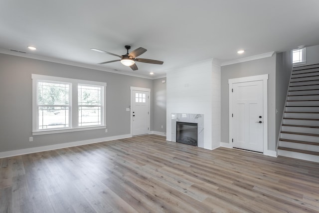 unfurnished living room with a fireplace, light wood-type flooring, ceiling fan, and ornamental molding