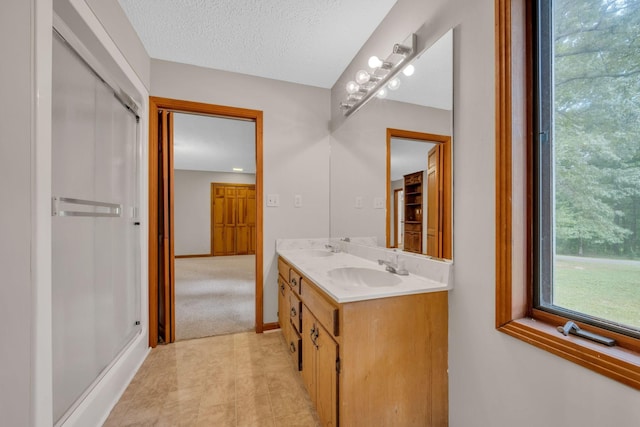 bathroom featuring vanity, an enclosed shower, and a textured ceiling