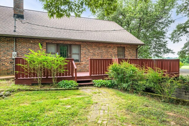 rear view of house with a wooden deck and a yard