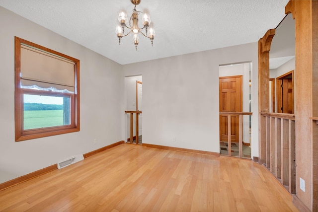 spare room featuring hardwood / wood-style flooring, a textured ceiling, and a notable chandelier