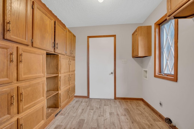 laundry area featuring cabinets, washer hookup, light wood-type flooring, a textured ceiling, and electric dryer hookup