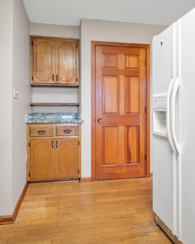 kitchen with light wood-type flooring and white refrigerator with ice dispenser