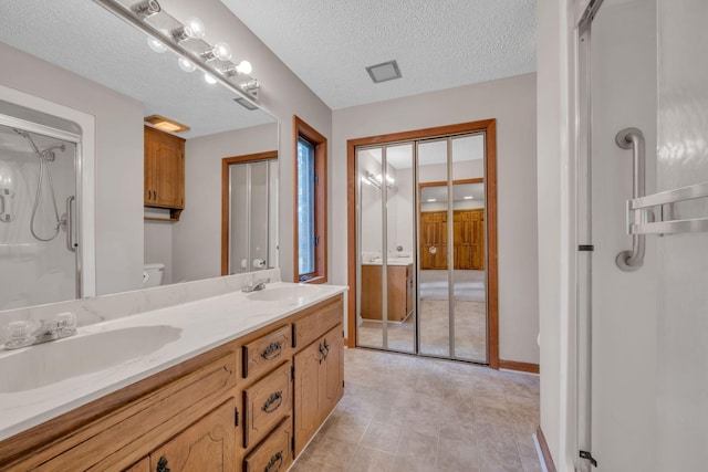 bathroom featuring vanity, toilet, a textured ceiling, and walk in shower