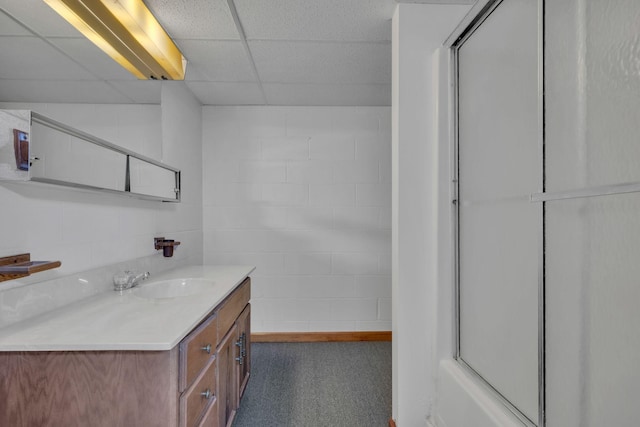 bathroom with a drop ceiling, vanity, and combined bath / shower with glass door