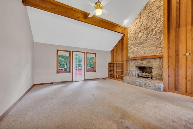 unfurnished living room with high vaulted ceiling, a stone fireplace, wooden walls, ceiling fan, and beam ceiling