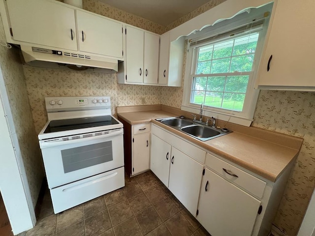 kitchen with white cabinets, white electric range oven, sink, and dark tile patterned flooring