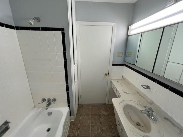 bathroom with shower / washtub combination, vanity, and tile walls