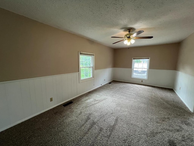 carpeted empty room with plenty of natural light, ceiling fan, and a textured ceiling